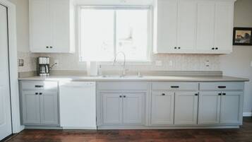 A kitchen with white cabinets, a window, and a dishwasher.