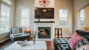 A living room with a fireplace, a large TV mounted above it, and a compass decoration on the wall.
