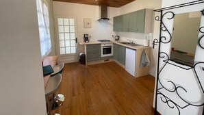 A compact kitchen with wooden flooring, a built-in oven, a sink, and light green cabinets. - Gite Jeanroy a Cheerful 2 Bedroom Rural Gite (Saint-Martial-Viveyrol)