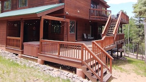 A two-story log cabin with a balcony and a staircase leading to an upper deck. - Mountain Cabin with Multi-level Decks, Views, Hot Tub, Family Memories Made Here (Angel Fire)