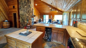 A spacious kitchen with a stone column, wooden cabinets, and a large island. - Mountain Cabin with Multi-level Decks, Views, Hot Tub, Family Memories Made Here (Angel Fire)