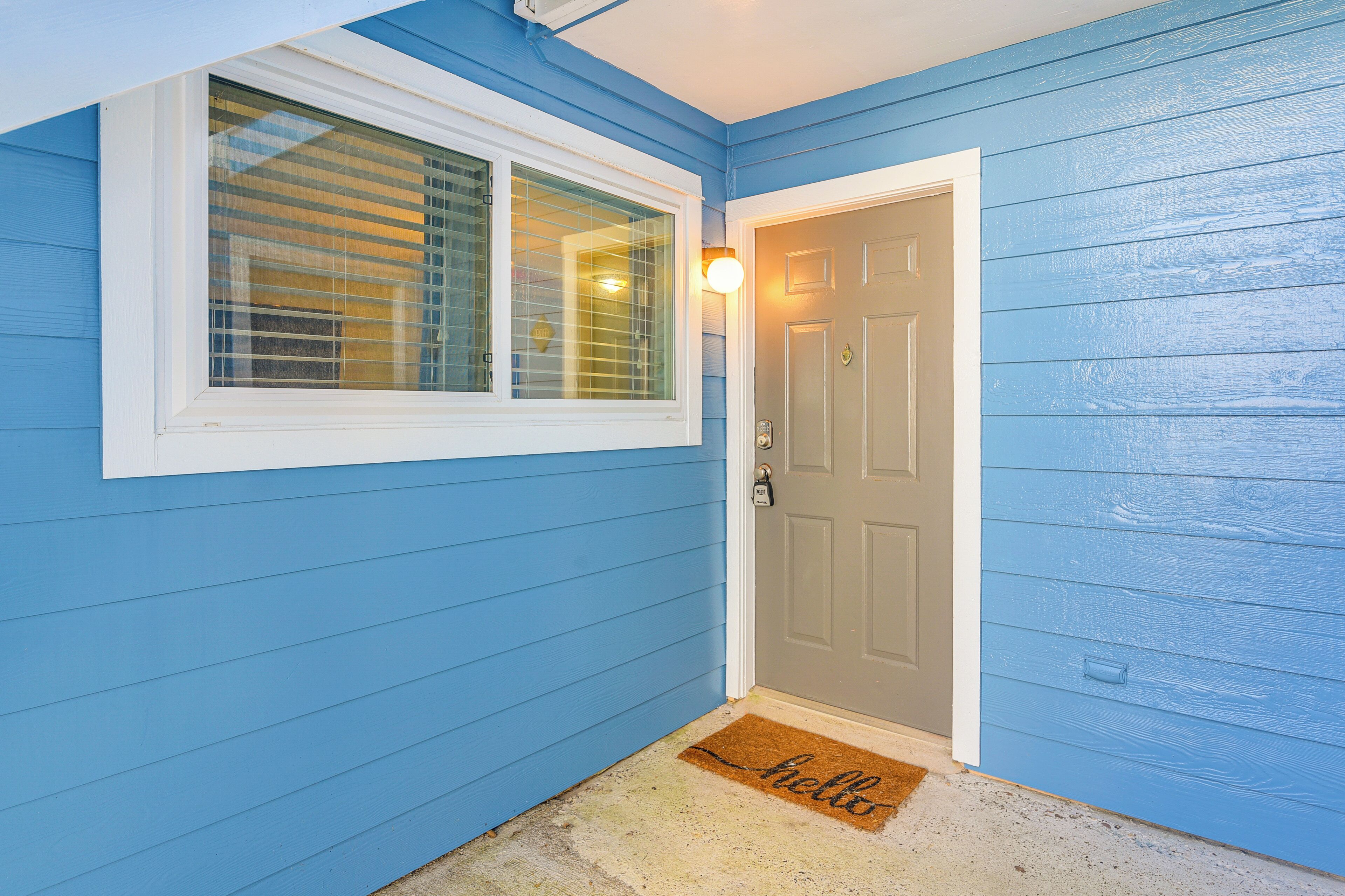 A blue exterior wall with a white-framed window and a door with a doorknob.