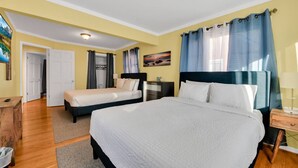 Une chambre d’hôtel avec un grand lit, deux petits lits, un bureau et une chaise.