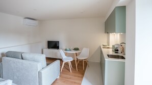 A modern, compact living space with a sofa, dining table, chairs, a TV, and a kitchenette. - Studio for 2 people * SPA * River view (Adaúfe)