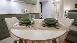 A dining area with a round table set for two, green bowls, wine glasses, and a white tablecloth. - Studio for 2 people * SPA * River view (Adaúfe)