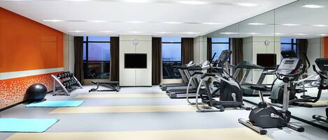 Un gimnasio moderno con cintas de correr, elípticas y pesas libres.