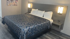 Une chambre d’hôtel moderne avec un grand lit, une tête de lit dotée de lampes murales, une table de chevet et un tableau accroché au mur.