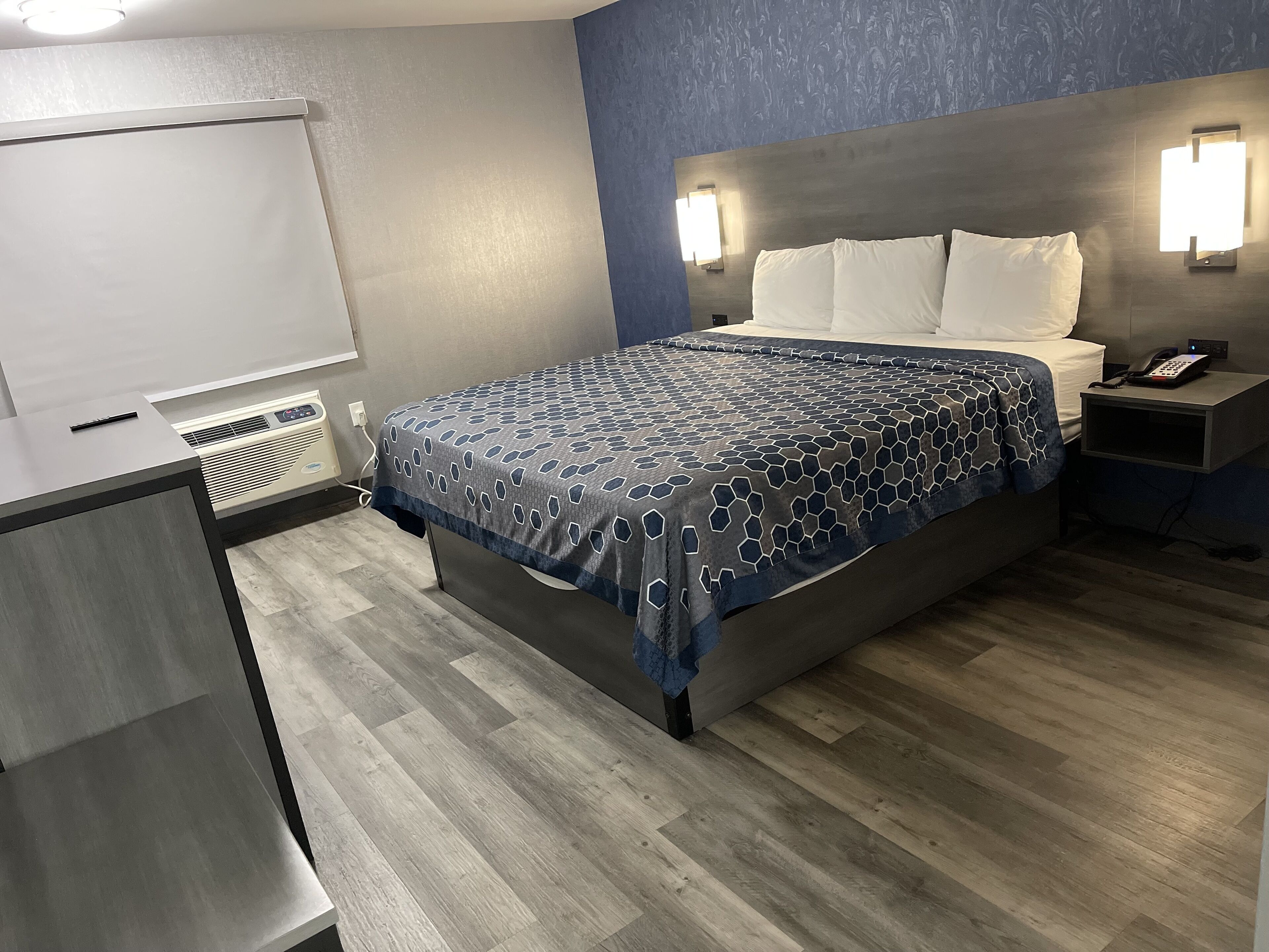 Una habitación de hotel con cama, mesita de noche y escritorio con silla.