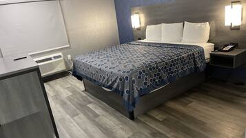 Una habitación de hotel con cama, mesita de noche y escritorio con silla.