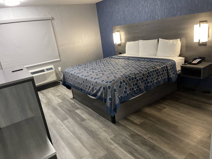 Una habitación de hotel con cama, mesita de noche y escritorio con silla.