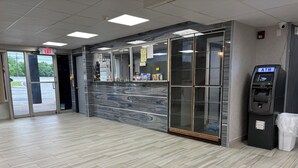 Un hall d’entrée propre et moderne, avec un mur en marbre, un distributeur automatique de billets et une porte vitrée donnant sur l’extérieur.