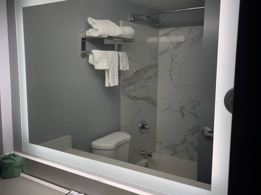 A modern bathroom with a large mirror, a toilet, a shower, and a sink.