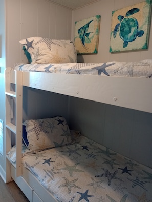 Una cama litera con ropa de cama temática de estrella de mar y dos cuadros de tortugas marinas.