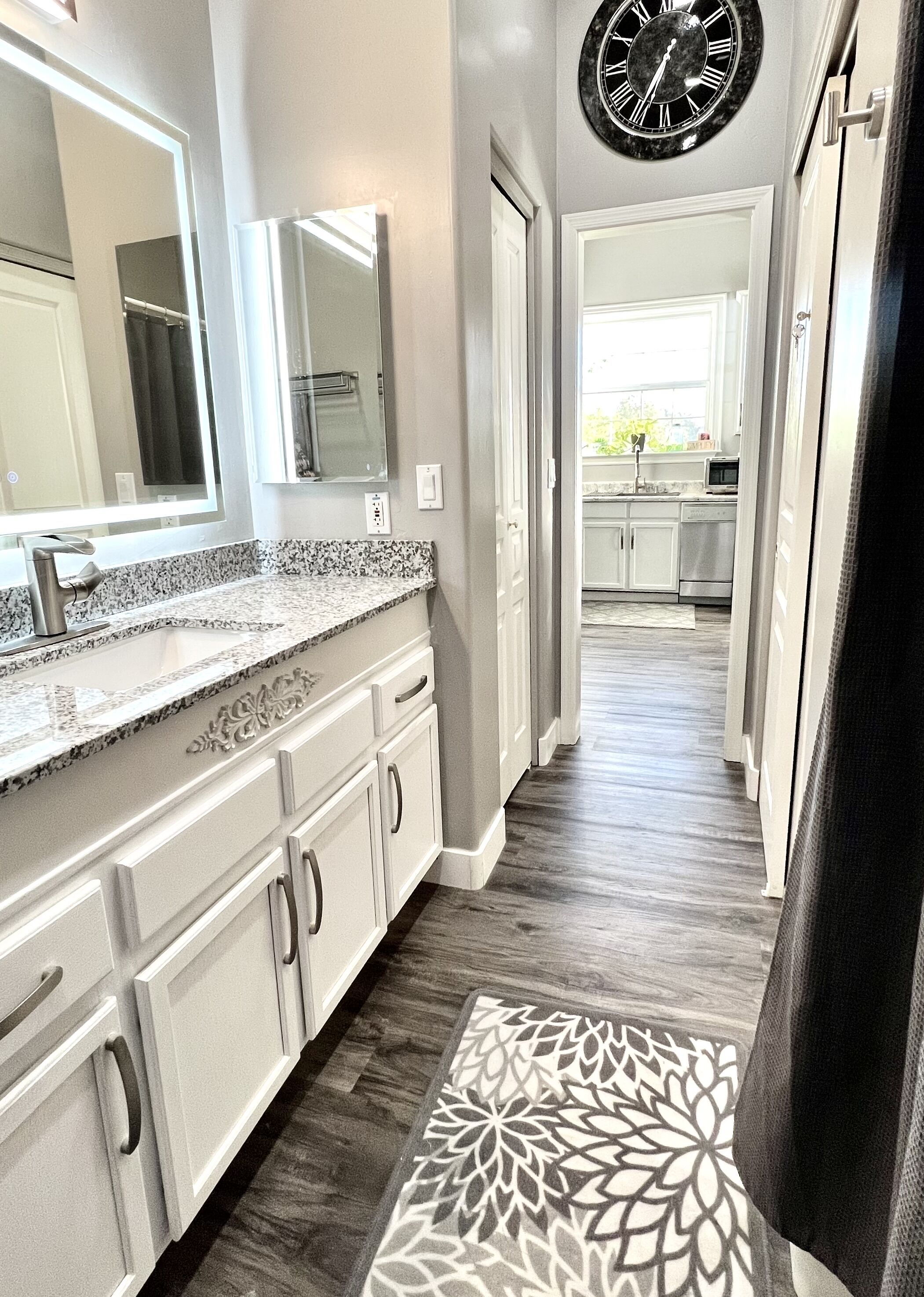 Una cocina moderna con encimera de granito, muebles de color blanco y una alfombra estampada.