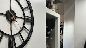 A modern interior with a large wall clock, a dining area with a wooden chair, and a kitchen area with a stove. - Country Living in the City (Mesa)