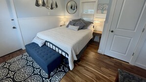 A bedroom with a bed, bedside tables, a bench, a chandelier, wall decorations, and a door. - Riverwalk Retreat on Main. Spacious updated Victorian Home in the heart of Niles (Niles)