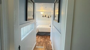 A narrow hallway with wooden flooring, white walls, and a bed in the distance. - Riverwalk Retreat on Main. Spacious updated Victorian Home in the heart of Niles (Niles)