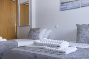 A hotel room with a neatly made bed, a wooden door, and a painting on the wall.
