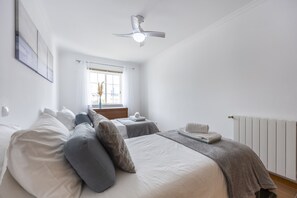 Een slaapkamer met een bed, nachtkastjes, een radiator en een raam met gordijnen.