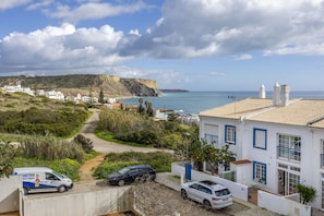 A coastal residential area with houses, a road, and a cliff.