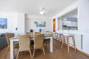 A modern living space with a dining area, kitchen, and a ceiling fan.