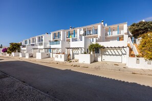 Een rij witte gebouwen met blauwe accenten, voorzien van balkons en schotels.