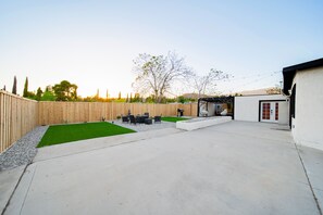 A backyard with a patio, a small lawn, and a wooden fence.