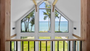 A room with large windows offering a view of the sea and trees.