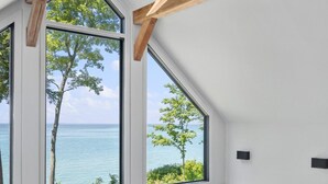 A modern interior with large windows offering a view of the sea and greenery.