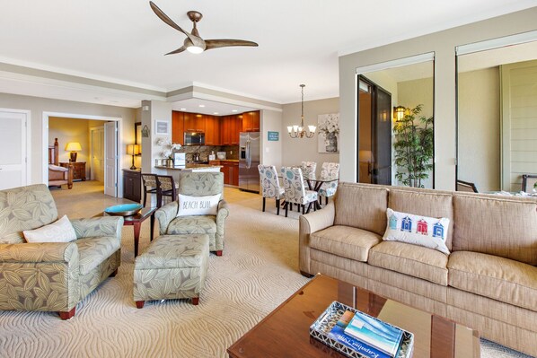 A spacious living room with a sofa, armchairs, a coffee table, and a dining area with chairs and a table.