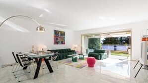 Ein modernes Wohnzimmer mit einem Glastisch, einem grünen Sofa und einem farbenfrohen abstrakten Gemälde.