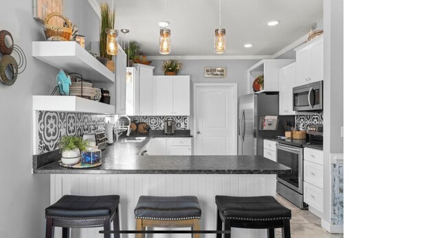 A kitchen with a central island, white cabinets, and a backsplash with black and white tiles.