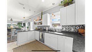 A modern kitchen with white cabinets, a black countertop, and a patterned backsplash.