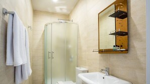 Een moderne badkamer met een douchecabine van glas, een wit wastafelmeubel en een spiegel erboven.