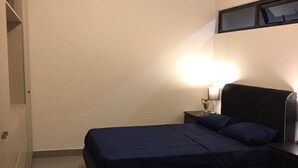 Een slaapkamer met een bed, een nachtkastje, een lamp en een zwart tapijt.