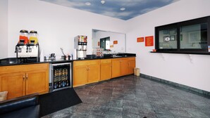 A modern kitchen with wooden cabinets, a black countertop, and a ceiling with a cloud design. - Palace Inn I10East & John Ralston (Houston)