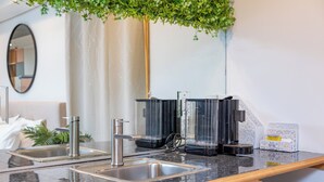 Une cuisine moderne équipée de deux éviers, d’une machine à café et d’une petite plante.