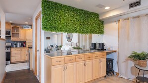 Une cuisine moderne avec des meubles en bois, un plan de travail en verre et une décoration murale verte.