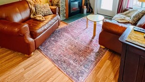 A living room with a fireplace, leather sofas, a coffee table, and a TV mounted on the wall. - Blue Knob Big Snow Condo  (Claysburg)
