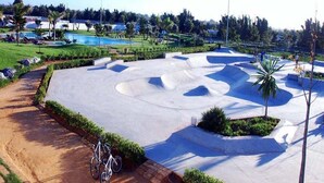 Una pista de skate con una rampa de hormigón y una bicicleta estacionada cerca.