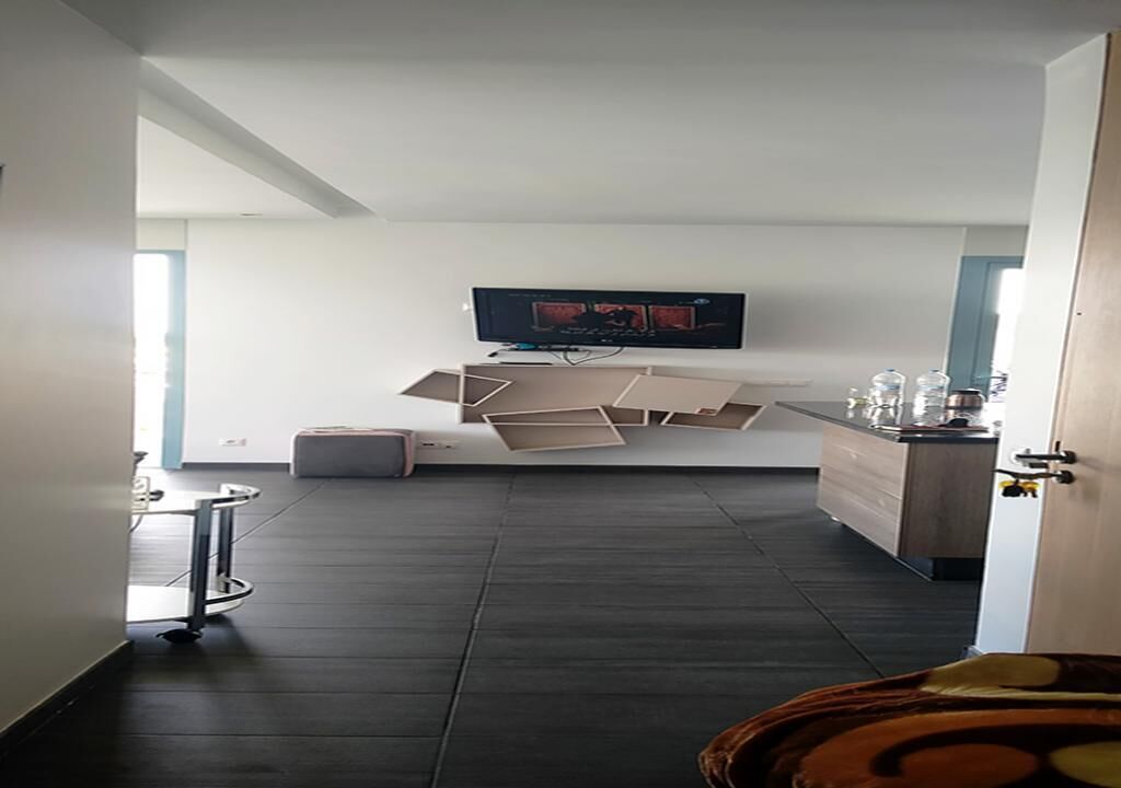 Ein modernes Zimmer mit einem an der Wand befestigten Flachbildfernseher, einem dunklen Holzboden und einem minimalistischen Design.