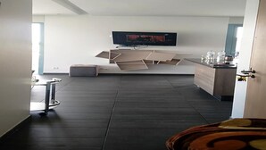 Una habitación moderna con un televisor de pantalla plana en la pared, suelo de madera oscura y un diseño minimalista.