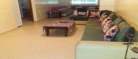 Uma sala de estar com sofá, mesa de centro e uma mesa pequena.