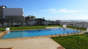 A swimming pool with a clear view of the ocean and a modern building in the background.
