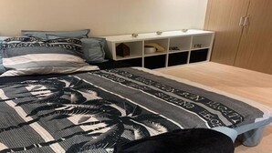 Ein Schlafzimmer mit Bett, Kissen, Nachttisch und Kleiderschrank.
