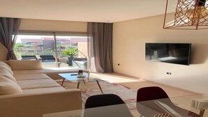 Ein modernes Wohnzimmer mit einer Couch, einem Glastisch und einem an der Wand befestigten Fernseher.
