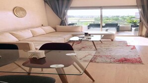 Ein modernes Wohnzimmer mit einer Couch, einem Glastisch und Blick ins Freie.