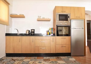 A kitchen with wooden cabinets, a stainless steel refrigerator, a microwave, and a coffee maker.