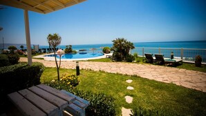 A pool area with a view of the sea, surrounded by a patio with lounge chairs and a wooden deck. - Residence La Source Taghazout 5217 (Taghazout)
