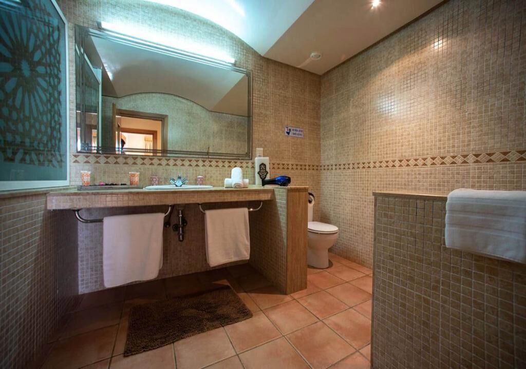 Un baño con lavamanos, espejo e inodoro.